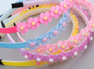Détail de serre-têtes fleurs en résine montrant les dents antidérapantes et couleurs variées