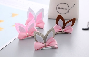 Detailed view of pink, brown, and grey bunny ear hair clips with bows and rhinestones