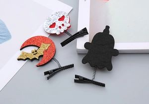 Close-up of Halloween hair clips with glitter skull, bat, and ghost on spring metal pins