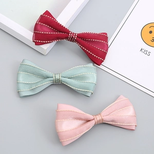 Detail of three handmade silk bow hair clips in red, blue, and pink for girls