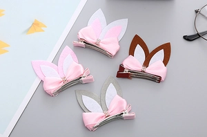 Close-up of four bunny ear hair clips with satin bows and sparkling rhinestone details
