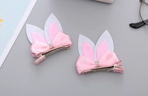 Detail of pink rabbit ear hair clips with satin bows and rhinestones on metal clips