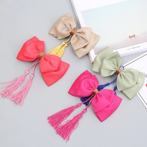 Detail of four handmade bow hair clips with long tassels in elegant vintage ribbon style