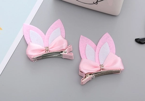 Close-up of pink felt rabbit ear hair clips with satin bows and sparkling rhinestones