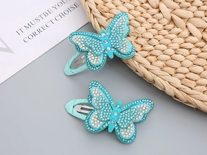 Detail of two blue butterfly hair clips with shimmering AB rhinestones on woven mat