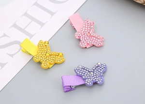 Vue détaillée de trois pinces à cheveux papillon ornées de strass brillants en rose et jaune