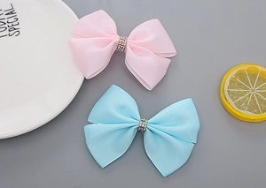 Detail von rosa und blauen Ripsband-Schleifen-Clips mit funkelnden Strass-Zentren