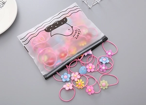 Close-up of girls' elastic hair ties with colorful flower charms and storage bag