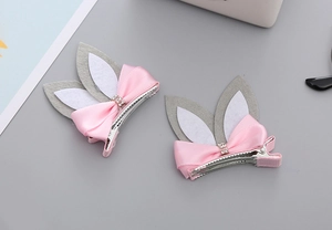 Detail of pink ribbon bow hair clips with grey bunny ears and sparkling rhinestone rings