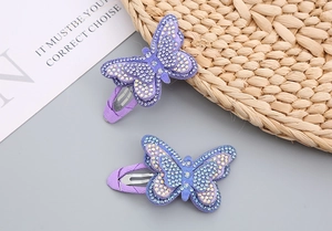 Detailed macro view of butterfly hair clips with shimmering rhinestones and purple fabric