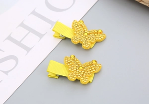 Détail de pinces à cheveux papillon jaunes avec strass brillants et ruban gros-grain