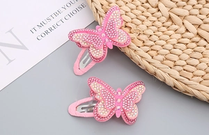 Close-up of pink butterfly hair clips with shimmering rhinestones and layered wings
