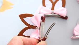 Detail of pink satin bow hair clip with rabbit ears and secure metal crocodile grip