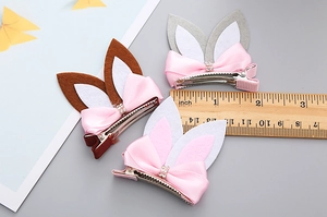 Detailed macro view of three cute rabbit ear hair clips with glittery bow accents