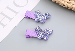 Détail de deux pinces à cheveux papillon violettes avec des strass brillants pour filles