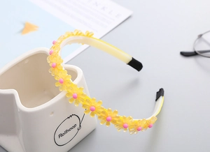 Détail d'un serre-tête fleurs jaunes en résine pour filles avec design antidérapant