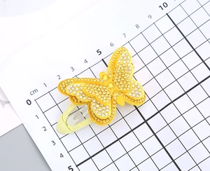 Macro shot of yellow butterfly hair clip with rhinestones and size measurement tool