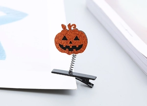 Detail of glittery orange pumpkin spring hair clip with black jack-o'-lantern face