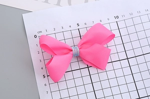 Vue détaillée de la barrette à nœud rose faite main pour filles avec décor pailleté bleu