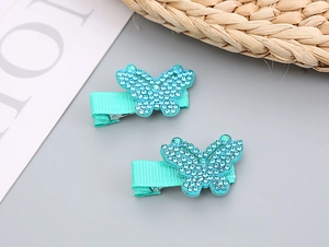 Détail de deux barrettes papillon bleu turquoise avec strass brillants pour petites filles