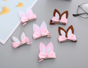 Close-up of cute rabbit ear hair clips with silk bows and rhinestone centers in soft felt