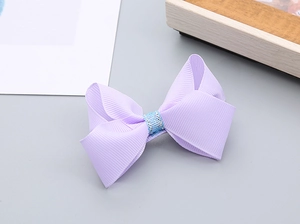 Détail d'un nœud papillon violet fait main avec des paillettes bleues pour cheveux de fille