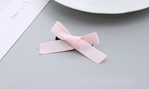 Detailansicht der rosafarbenen Haarklammer aus Ripsband auf minimalistischem grauem Grund
