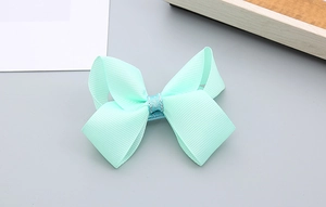 Détail du nœud papillon vert menthe avec paillettes argentées pour cheveux de fille