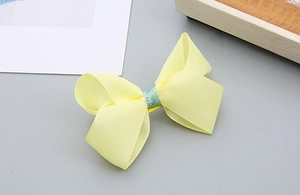 Détail du nœud de cheveux en gros-grain jaune avec centre en paillettes bleues