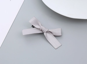 Detailansicht einer grauen Satin-Schleifen-Haarklammer mit feiner Textur und Entenschnabel