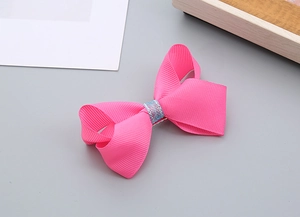 Détail de la barrette à nœud en ruban gros-grain rose avec fil bleu pailleté