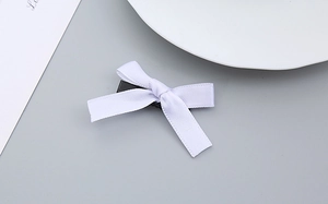 Detailansicht einer weißen Satin-Schleife Haarspange mit schwarzem Metall-Krokodilclip