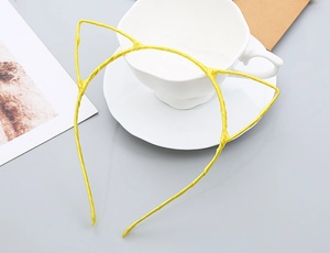 Detail of yellow cat ear headband wrapped in fabric on a desk with a white coffee cup