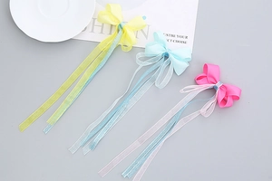 Vue détaillée de longs nœuds papillon en ruban jaune, bleu et rose pour filles