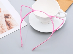 Pink cat ear headband displayed on a white ceramic cup with a minimalist grey background