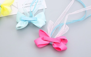 Vue détaillée des barrettes à nœuds faits main avec de longs rubans en organza et fils dorés