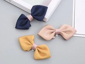 Detailed view of handmade bow ties in navy, pink, and yellow with secure back rings