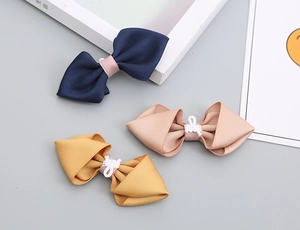 Detailed close-up of handmade kids' bow ties in navy, pink, and ginger textured fabric
