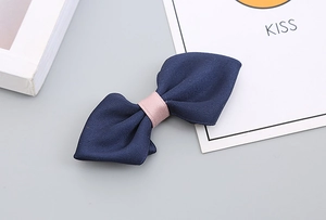 Close-up of handmade navy twill bow tie with pink ribbon on a minimalist background