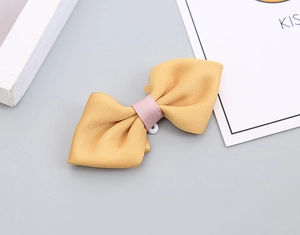 Detail of handmade dual-tone bow tie in mustard yellow and soft pink fine fabric