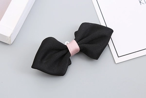 Detailed macro view of the black fabric bow tie with a soft pink satin ribbon accent