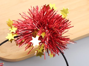 Close-up of red glitter ball headband with gold stars for parties on wooden tray