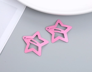 Detail of two pink star-shaped metal hair clips with hollow design on grey background