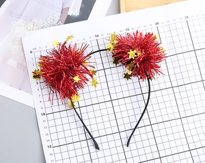 Close-up of festive headband featuring red pom-poms and shiny gold mirror stars