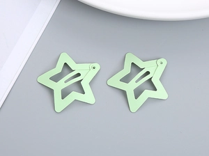 Close-up of two mint green star-shaped metal hair clips with a matte frosted finish