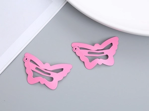 Detail view of pink butterfly snap hair clips for girls on a clean grey background