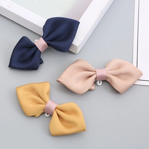 Three solid colored handmade bow ties for kids in navy blue, dusty pink, and bright yellow