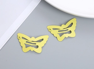 Detail of two yellow butterfly snap clips for girls with a matte finish and镂空 hollow design