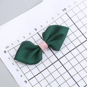 Deep green fabric bow with pink ribbon center on scale measurement board, 8cm long
