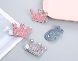 Vista detallada de pinzas para el cabello tejidas con formas de corona y pez con diamantes